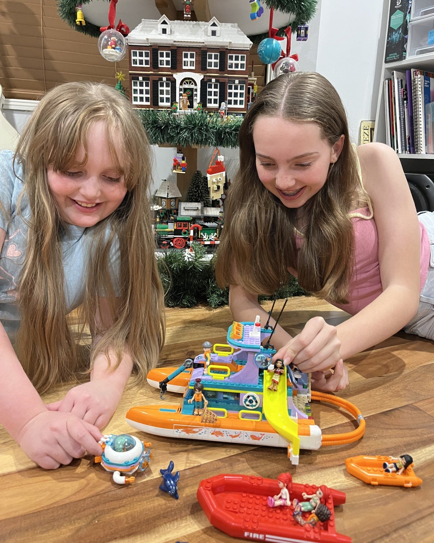 Two children playing withLEGO on a wooden table in a room